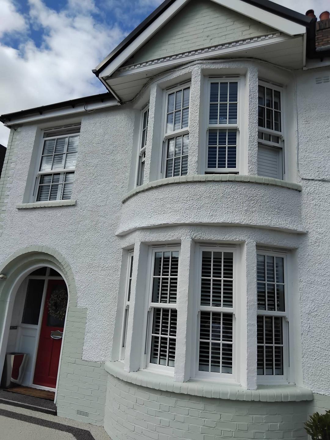 Same house after a full exterior repaint in fresh white render with soft sage bay and plinth detailing